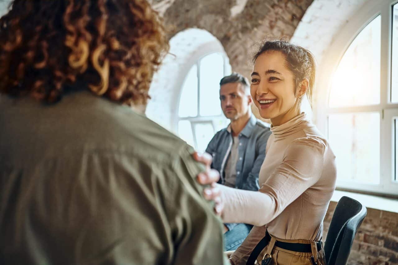 A supportive woman at Prairie Recovery Center offers comfort to a man in group therapy, highlighting the center's focus on connection during inpatient rehab