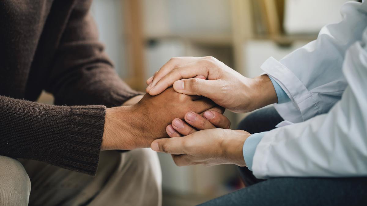 Therapist holding client's hands and supporting them in recovery.