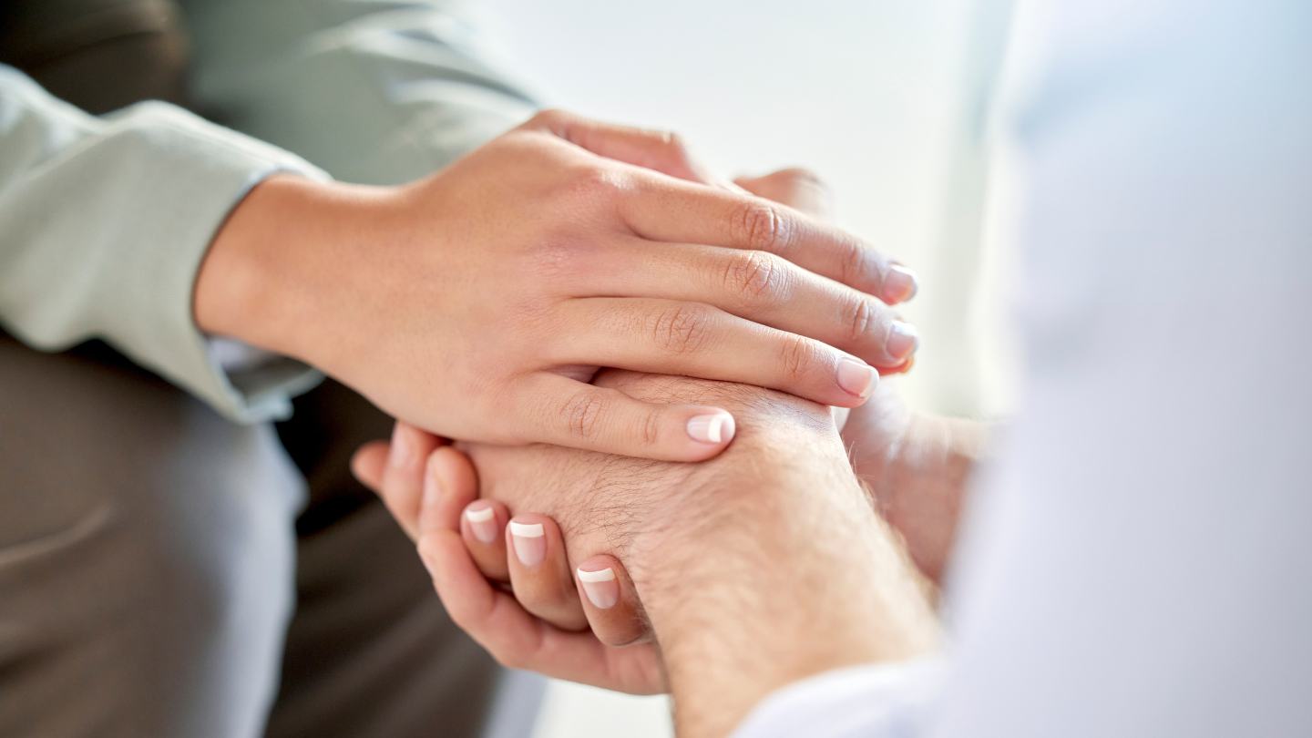 Supportive person holding the hand of someone in addiction treatment.