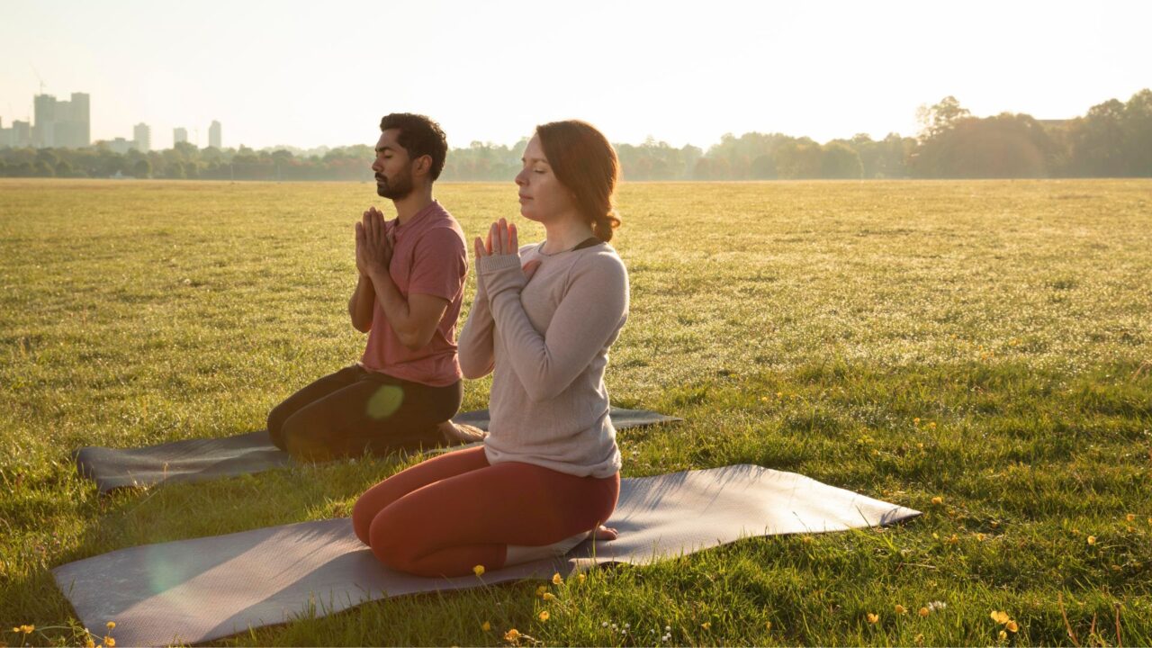 Two people practicing yoga in the outdoor area of the Austin residential rehab facility.