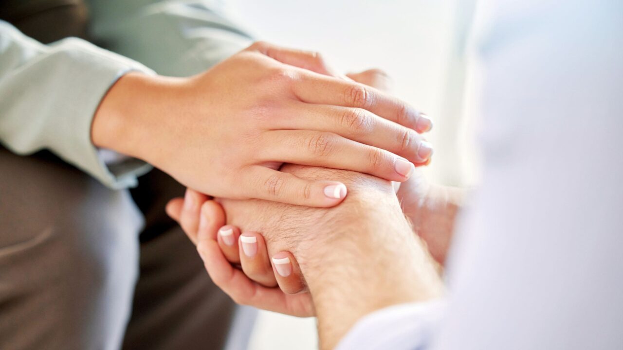 Supportive person holding the hand of someone in addiction treatment.