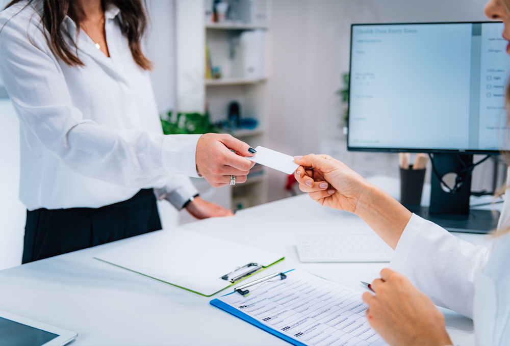 a-woman-handing-an-insurance-card-back